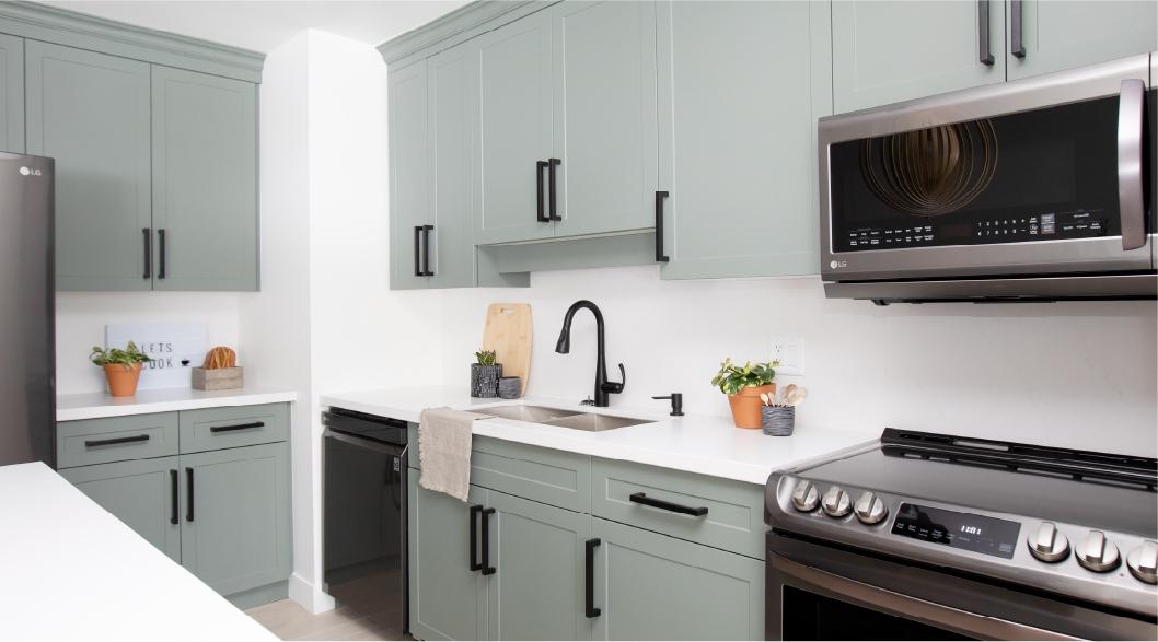 Sage Shaker cabinet fronts and black handles in a refreshed kitchen